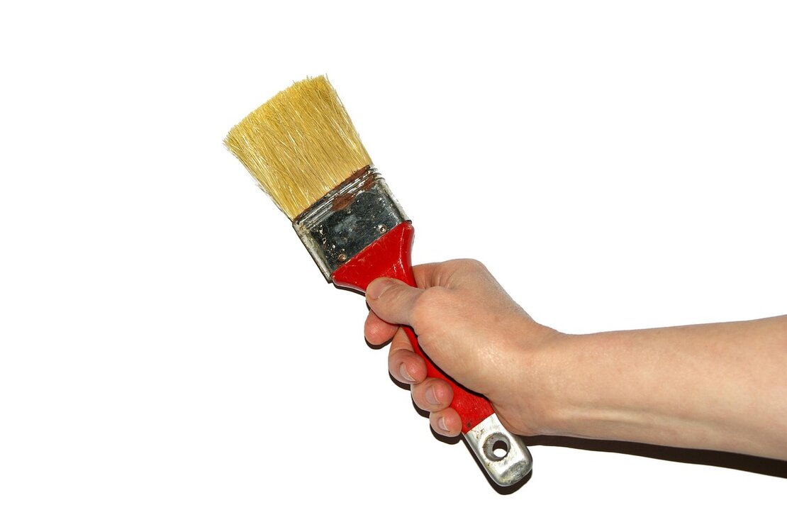 Handwerker bessert eine Wand mit Farbe aus
